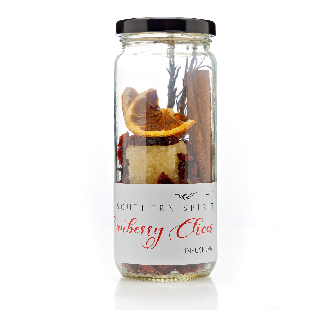 A glass cocktail infusion containing orange-Infused Organic Sugar, Unsweetened Cranberry, Rosemary, Cinnamon, Orange